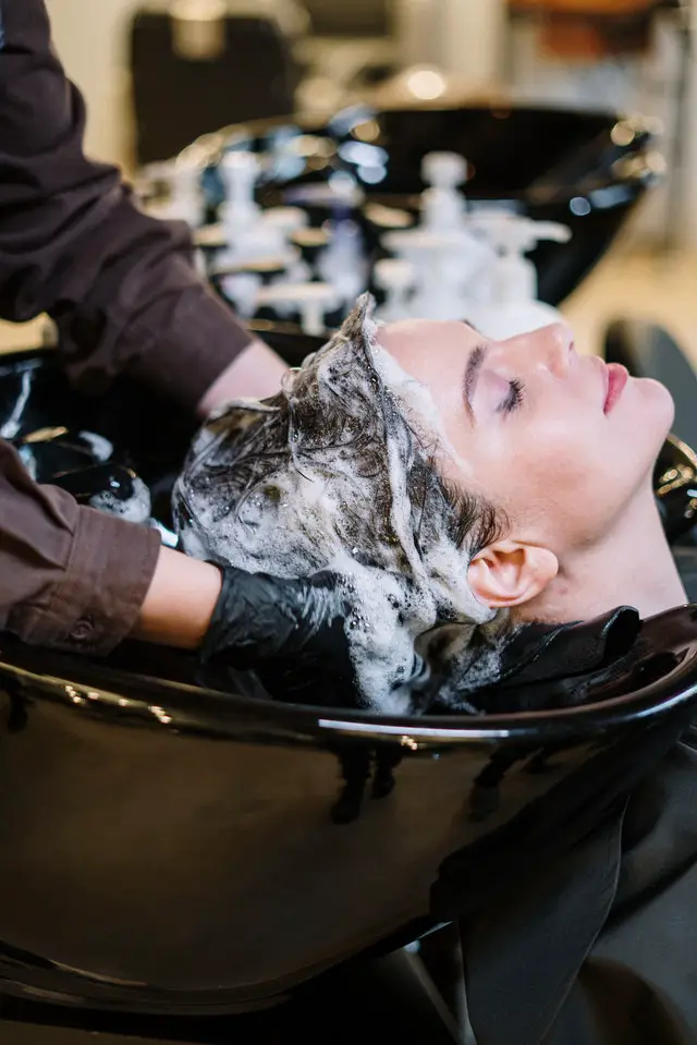 A girls hair being washed by a hairstylist in a salon